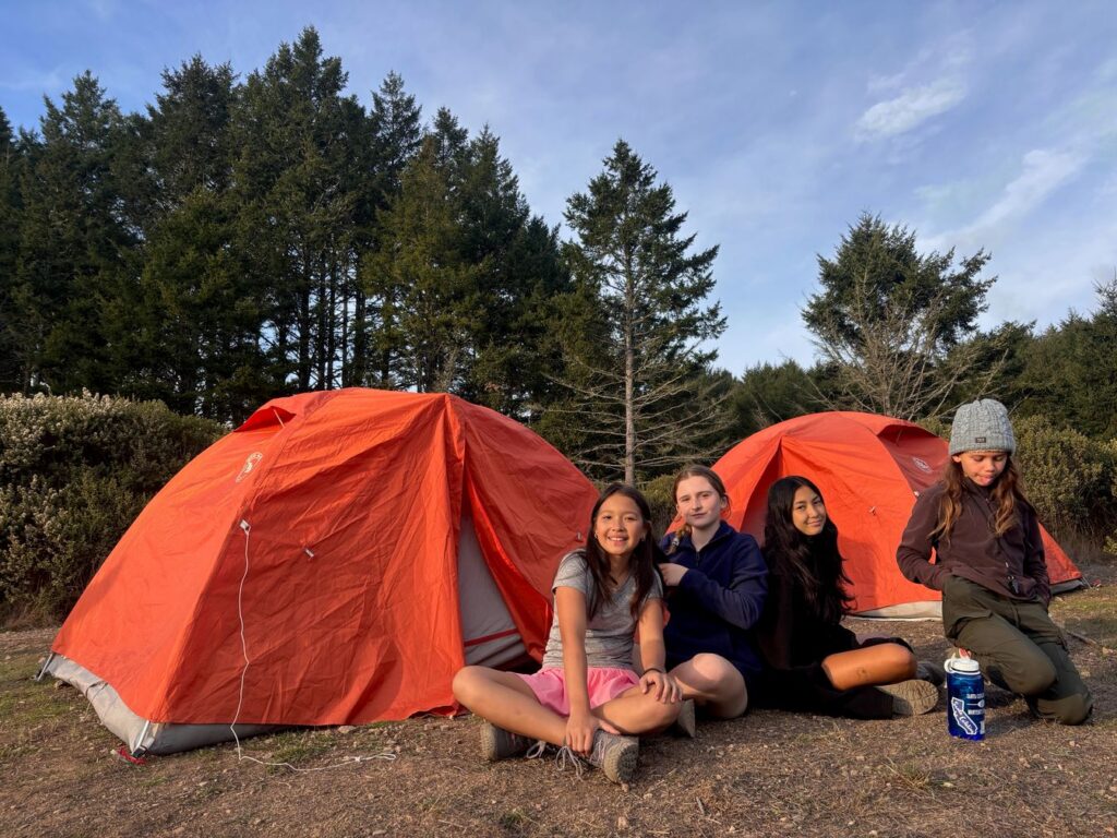 Students sitting by camping tents