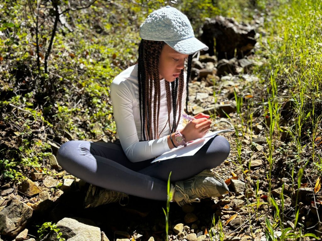 Student sitting in nature and journaling